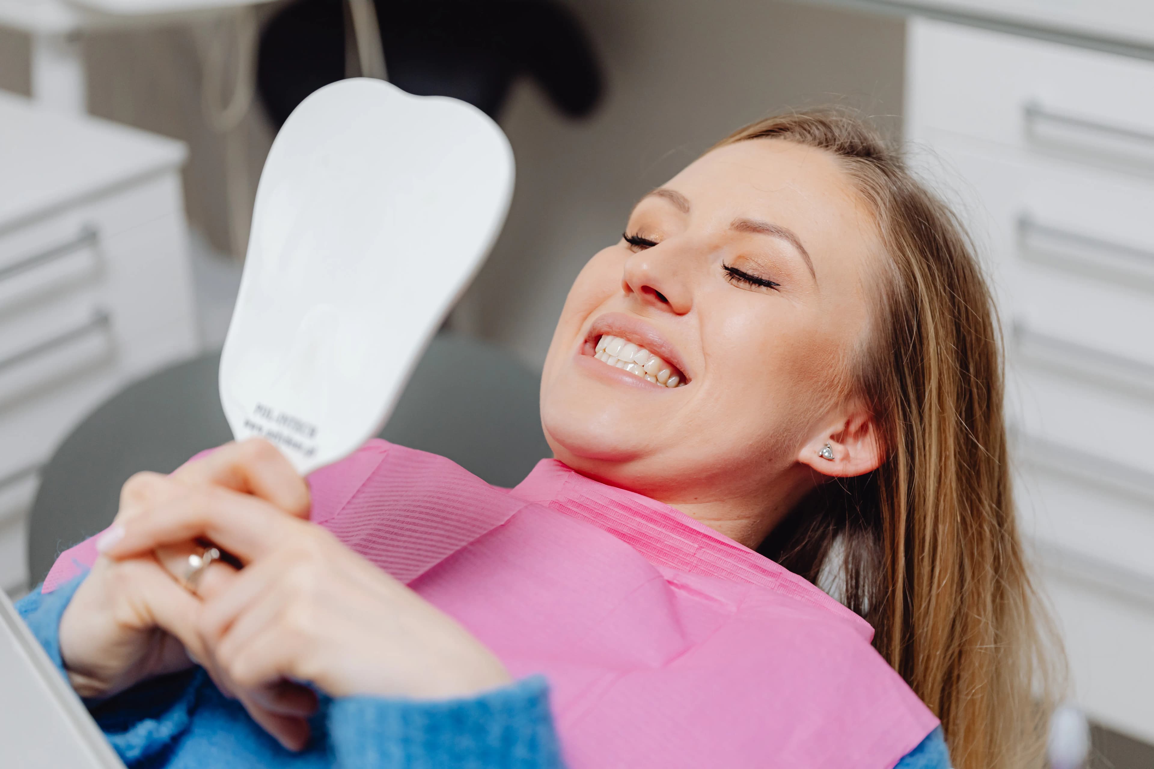 Smiling woman in dentist chair looking in a mirror